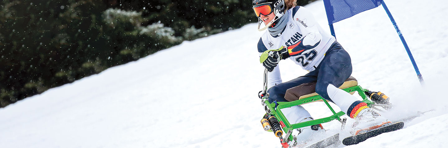 A man wearing goggles riding a snow bike down a snowy mountain