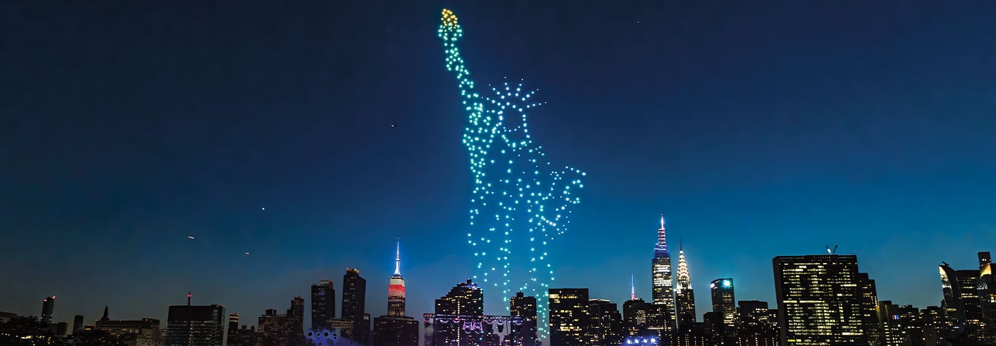 Image of a Statue of Liberty presented in lights over skyline of NYC