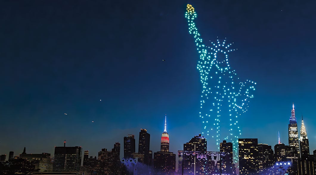 Image of a Statue of Liberty presented in lights over skyline of NYC