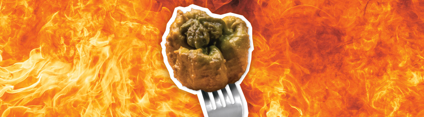 Image of the Pepper X on a fork against backdrop of flames