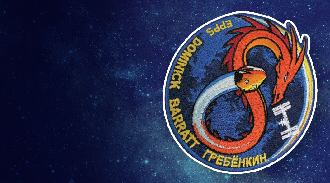 An embroidered patch shows a dragon encircling Earth, labeled Epps, Dominick, Barratt, & Гребёнкин