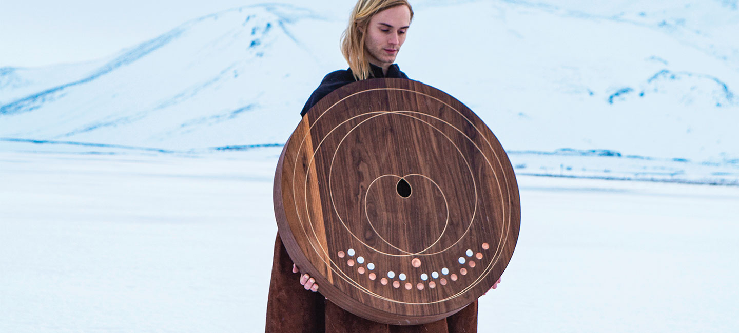 A person holding a giant wooden desk with a pattern of dots and concentric circles